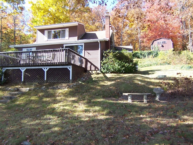 back of house with a chimney, a deck, and a yard