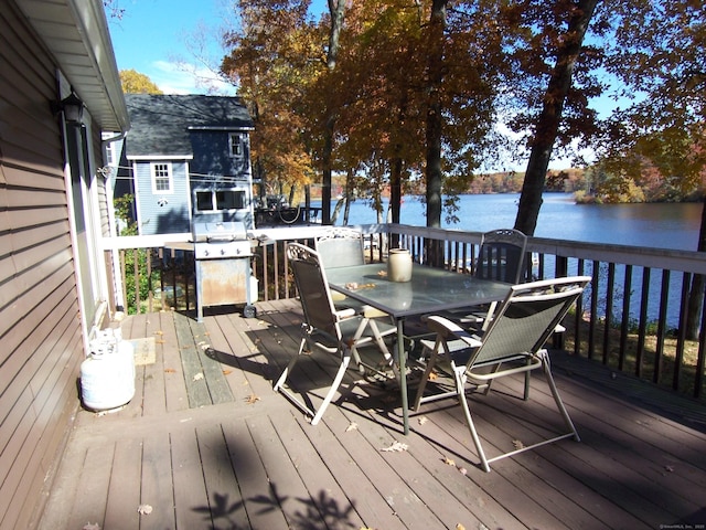 wooden terrace featuring a water view, a grill, and outdoor dining area