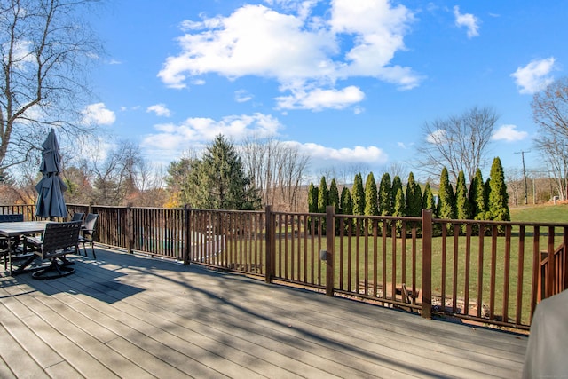 wooden deck featuring a lawn and outdoor dining space