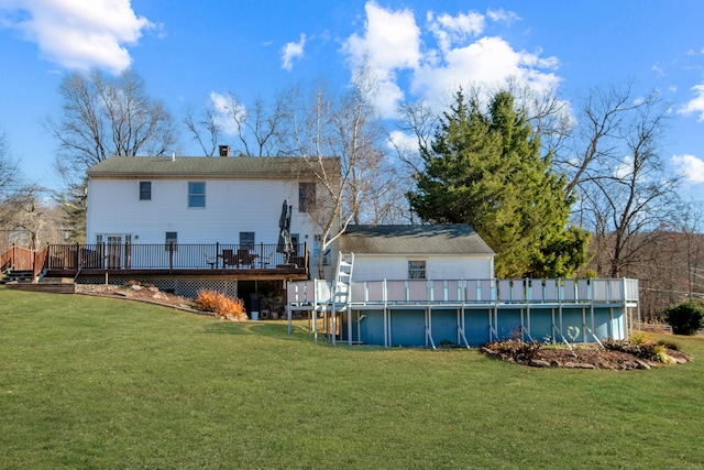 back of property featuring an outdoor pool, a chimney, a deck, and a yard