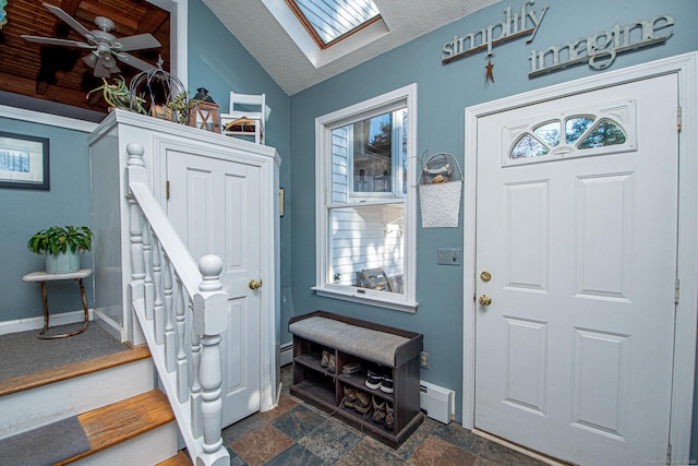 foyer with lofted ceiling with skylight, stone finish flooring, a textured ceiling, baseboards, and stairs