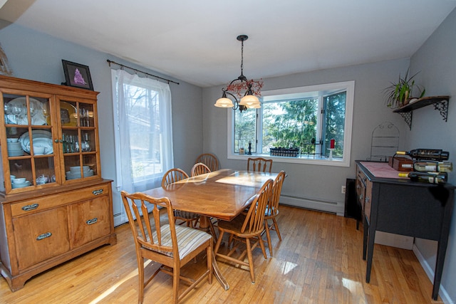 dining space with a baseboard heating unit, light wood-type flooring, and a notable chandelier