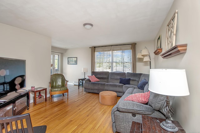 living room with baseboard heating, light wood-style flooring, and baseboards