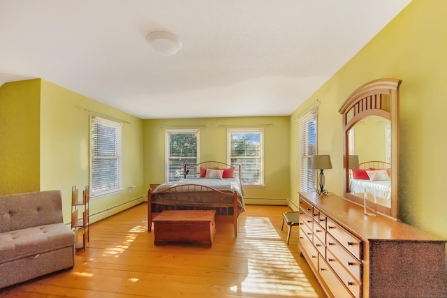 bedroom featuring a baseboard heating unit and light wood-type flooring