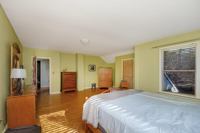 bedroom featuring lofted ceiling, wood finished floors, and baseboards