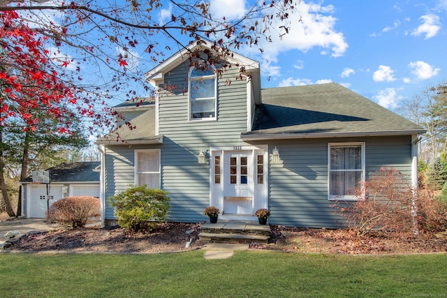 traditional-style home with an attached garage, roof with shingles, and a front yard