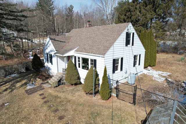 view of front of house with a shingled roof, a chimney, and fence