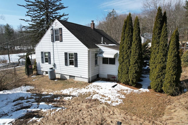 snow covered property featuring a shingled roof, fence, and a chimney