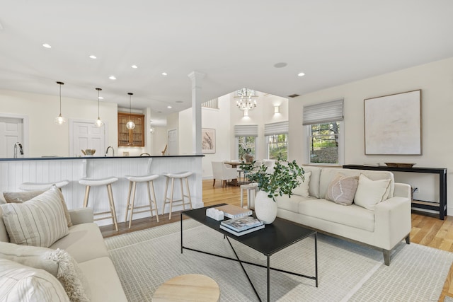 living area with light wood-type flooring, recessed lighting, baseboards, and an inviting chandelier