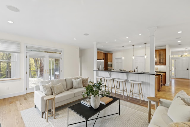 living area with light wood-style floors, baseboards, decorative columns, and recessed lighting
