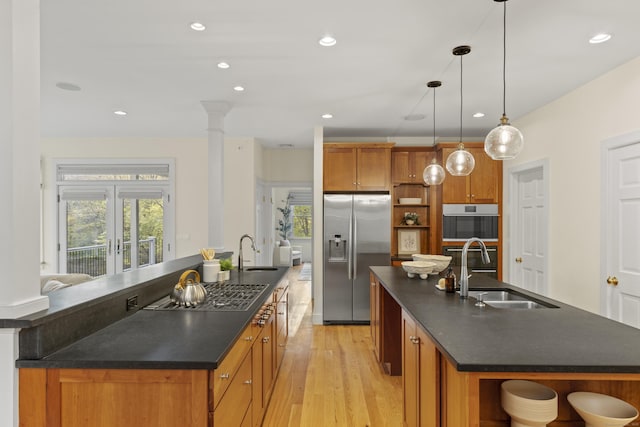 kitchen with dark countertops, a center island with sink, open shelves, and stainless steel appliances
