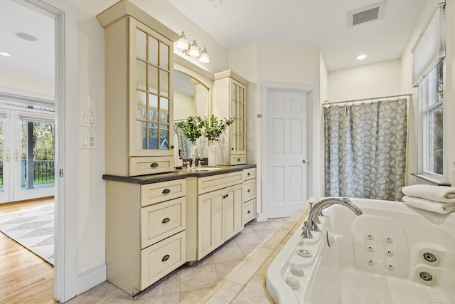 full bathroom featuring visible vents, french doors, a tub with jets, and vanity
