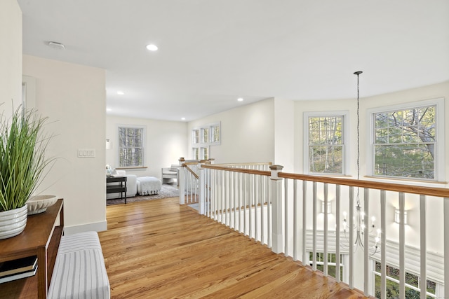 corridor featuring plenty of natural light, recessed lighting, wood finished floors, and an upstairs landing