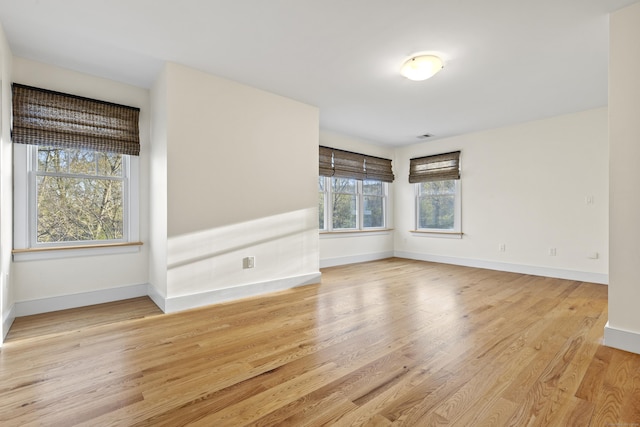 spare room with baseboards, visible vents, and wood finished floors