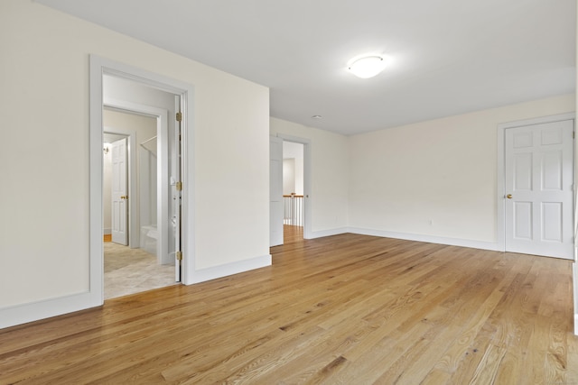 empty room with baseboards and light wood-type flooring