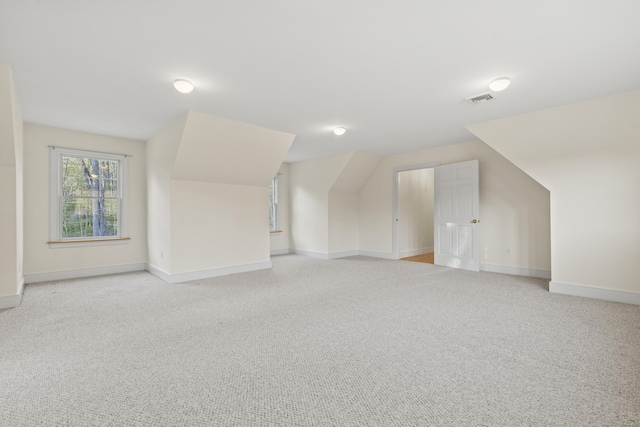 additional living space featuring light colored carpet, baseboards, and visible vents