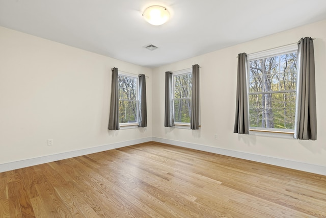 empty room with baseboards, wood finished floors, and visible vents