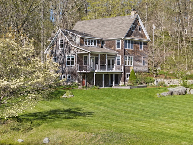 rear view of house featuring roof with shingles, a chimney, a yard, and a deck