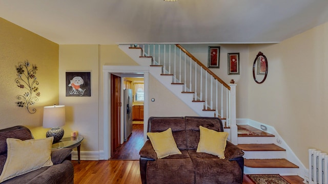 stairs featuring radiator heating unit, wood finished floors, and baseboards