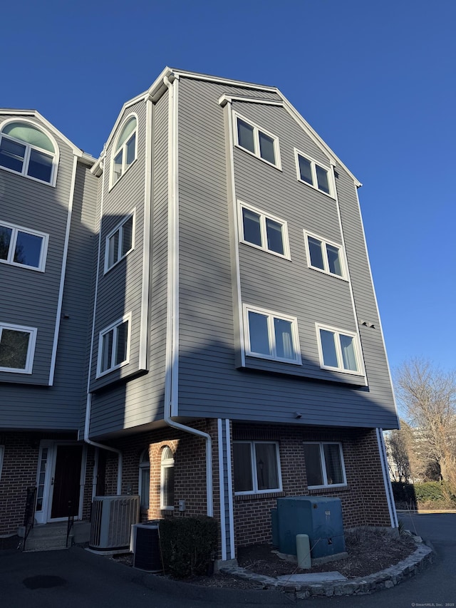 exterior space featuring cooling unit and brick siding