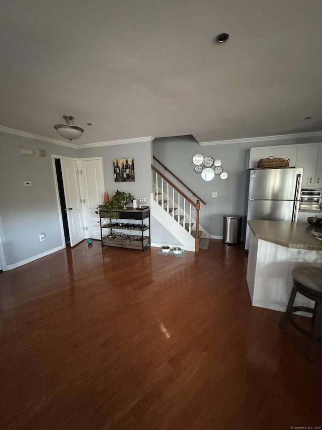 unfurnished living room with dark wood-style flooring, crown molding, baseboards, and stairs