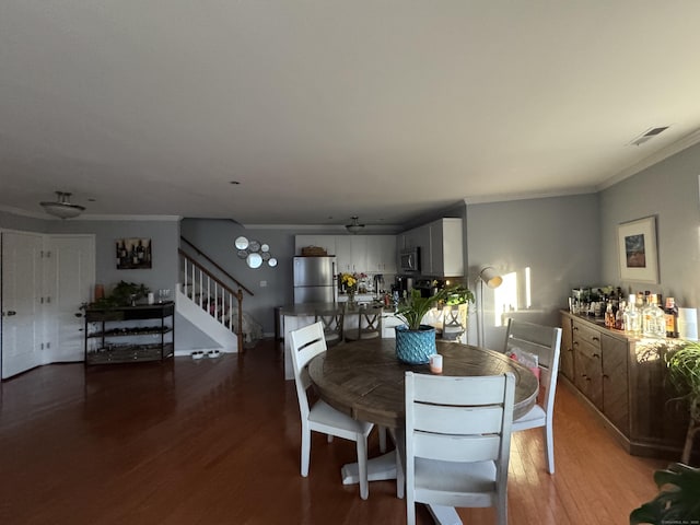 dining space with ornamental molding, visible vents, stairway, and wood finished floors