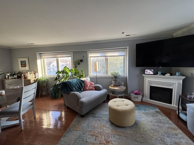 living area with crown molding, a fireplace, visible vents, and wood finished floors