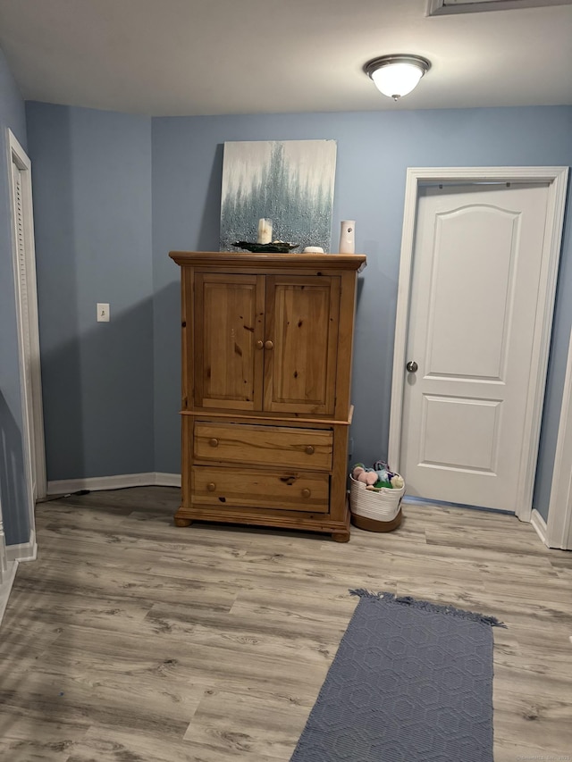 interior space featuring baseboards and light wood finished floors