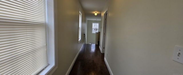 corridor featuring baseboards and dark wood-type flooring