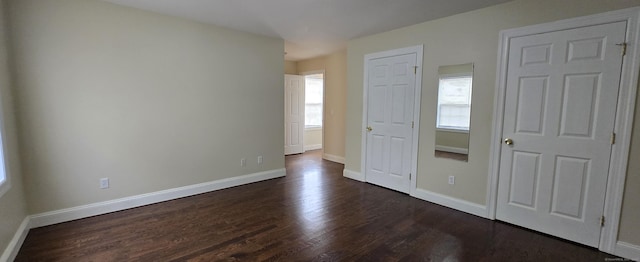 unfurnished bedroom featuring dark wood-style flooring and baseboards