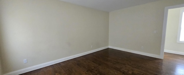 spare room with dark wood finished floors and baseboards