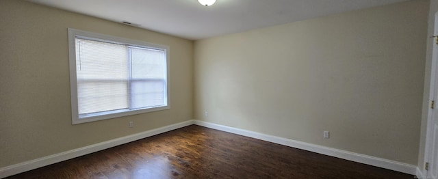 spare room featuring dark wood-style floors and baseboards