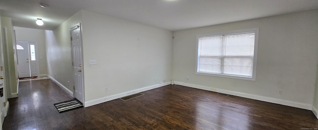 unfurnished room featuring visible vents, dark wood finished floors, and baseboards