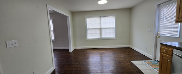 unfurnished dining area with dark wood finished floors and baseboards