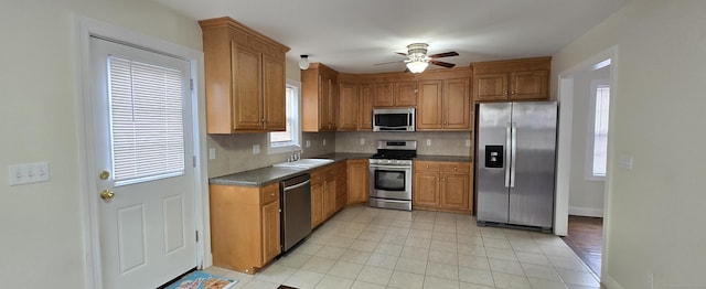 kitchen featuring brown cabinetry, backsplash, stainless steel appliances, and a sink