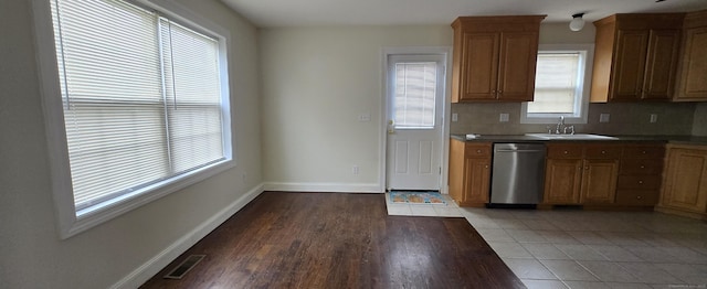 kitchen with tasteful backsplash, visible vents, a sink, dishwasher, and baseboards