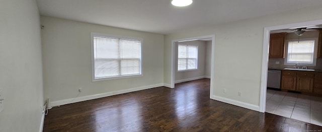 interior space featuring ceiling fan, a sink, baseboards, and wood finished floors