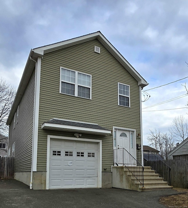 traditional-style house featuring aphalt driveway, fence, and a garage