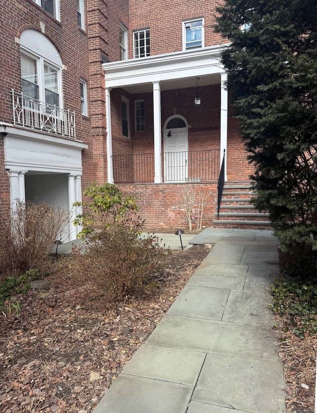 property entrance featuring covered porch and brick siding