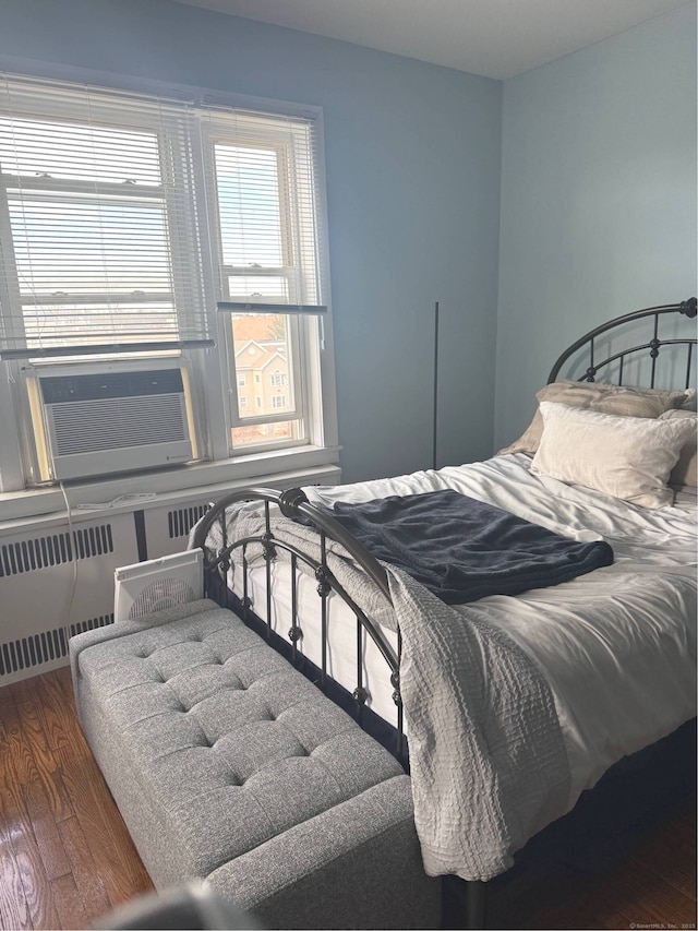 bedroom featuring radiator heating unit, cooling unit, and wood finished floors