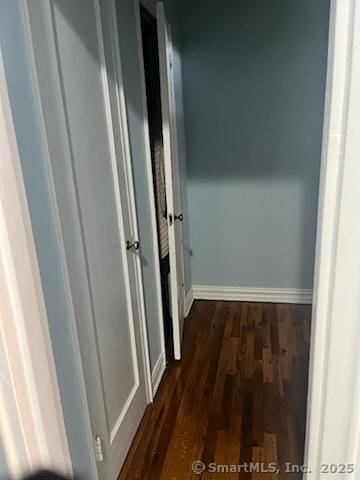 hallway featuring baseboards and dark wood-style flooring