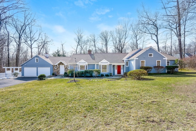 view of front of house with a chimney, a front yard, an attached garage, and driveway