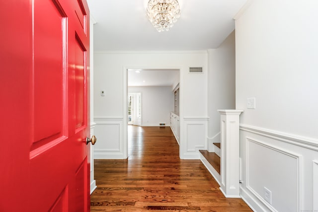 entryway with visible vents, a decorative wall, stairway, an inviting chandelier, and wood finished floors