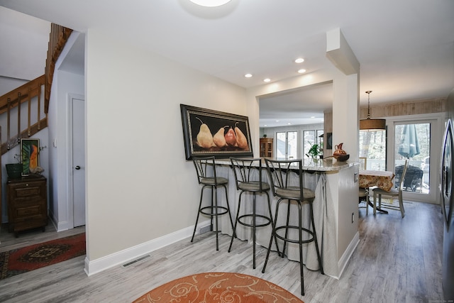 kitchen featuring a kitchen bar, recessed lighting, visible vents, light wood-type flooring, and baseboards