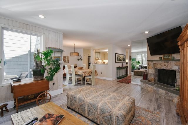 living area with light wood finished floors, a fireplace, baseboards, and a wealth of natural light