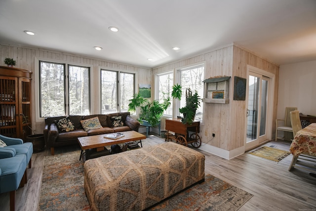 living room with recessed lighting, wood walls, and wood finished floors