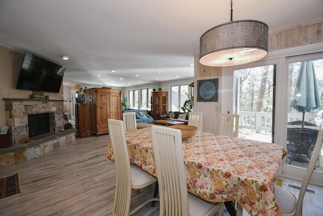 dining space with a stone fireplace, wood finished floors, visible vents, and recessed lighting