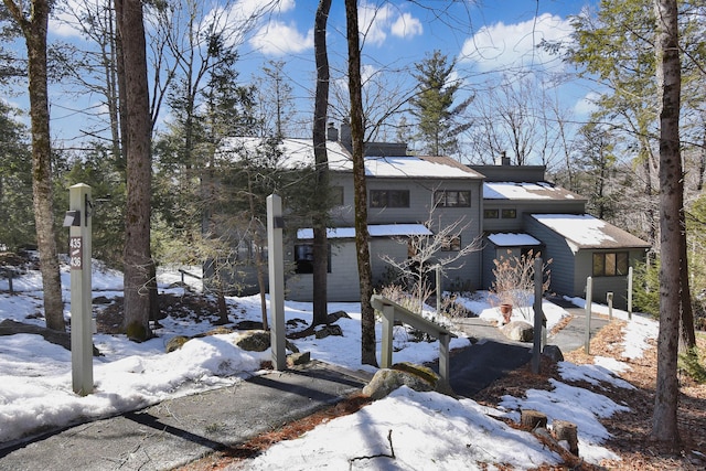 view of snowy exterior featuring a garage and a chimney