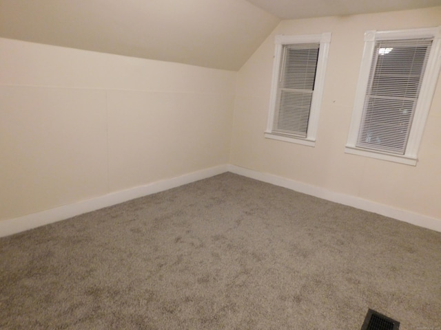 additional living space with carpet flooring, baseboards, visible vents, and vaulted ceiling