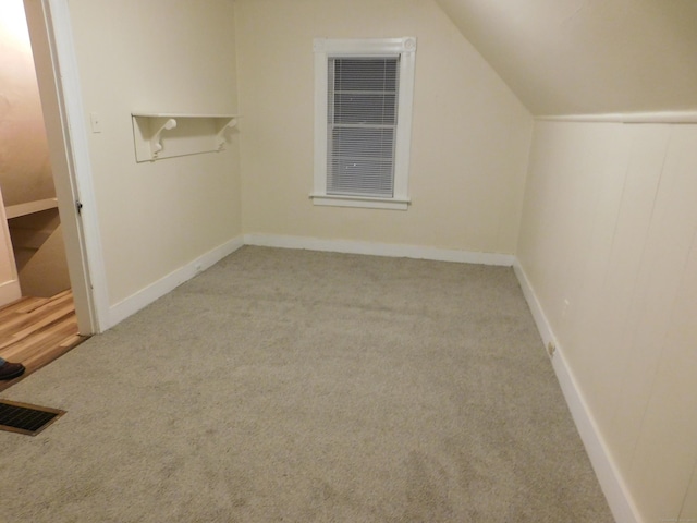 additional living space with visible vents, carpet floors, and vaulted ceiling